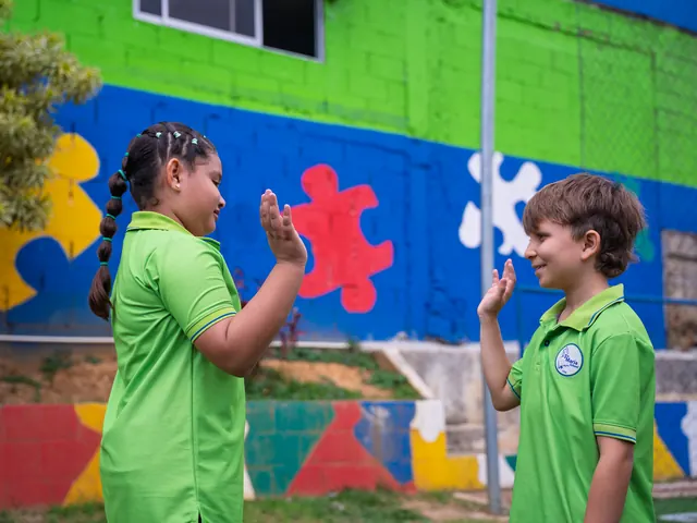 Dos estudiantes de Primaria chocando las manos en el patio