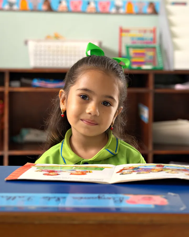 Niña de Preescolar con su libro en el aula