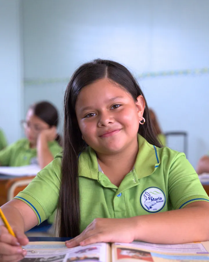 Estudiante de Primaria sonriendo mientras trabaja en su cuaderno