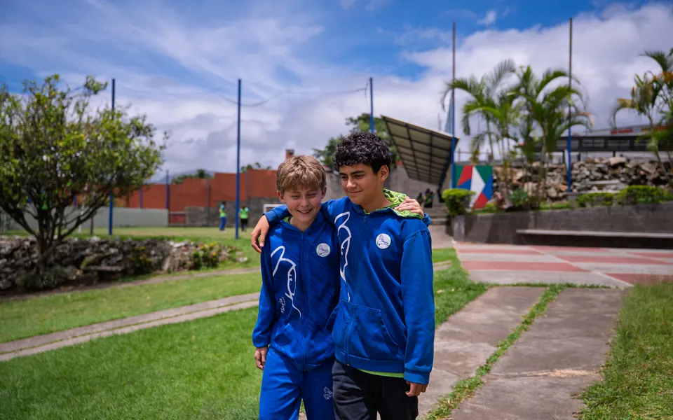 Dos estudiantes con el uniforme de educación física caminando por el campus